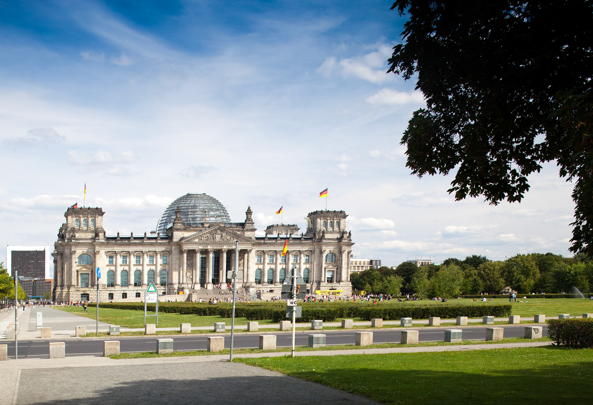 The Reichstag building in Berlin stands prominently with its iconic dome against a clear sky, inviting visitors to explore its history.