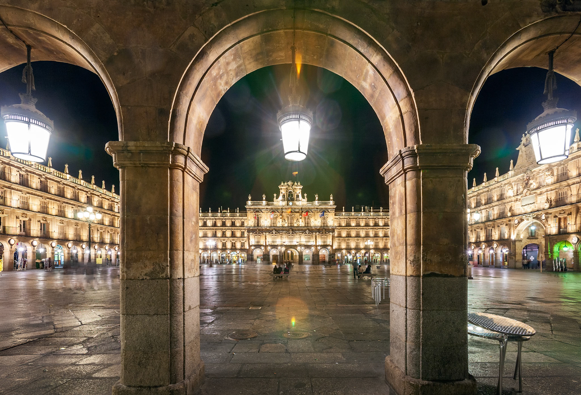 The Plaza Mayor in Salamanca beautifully illuminated at night seen through its stone portals.