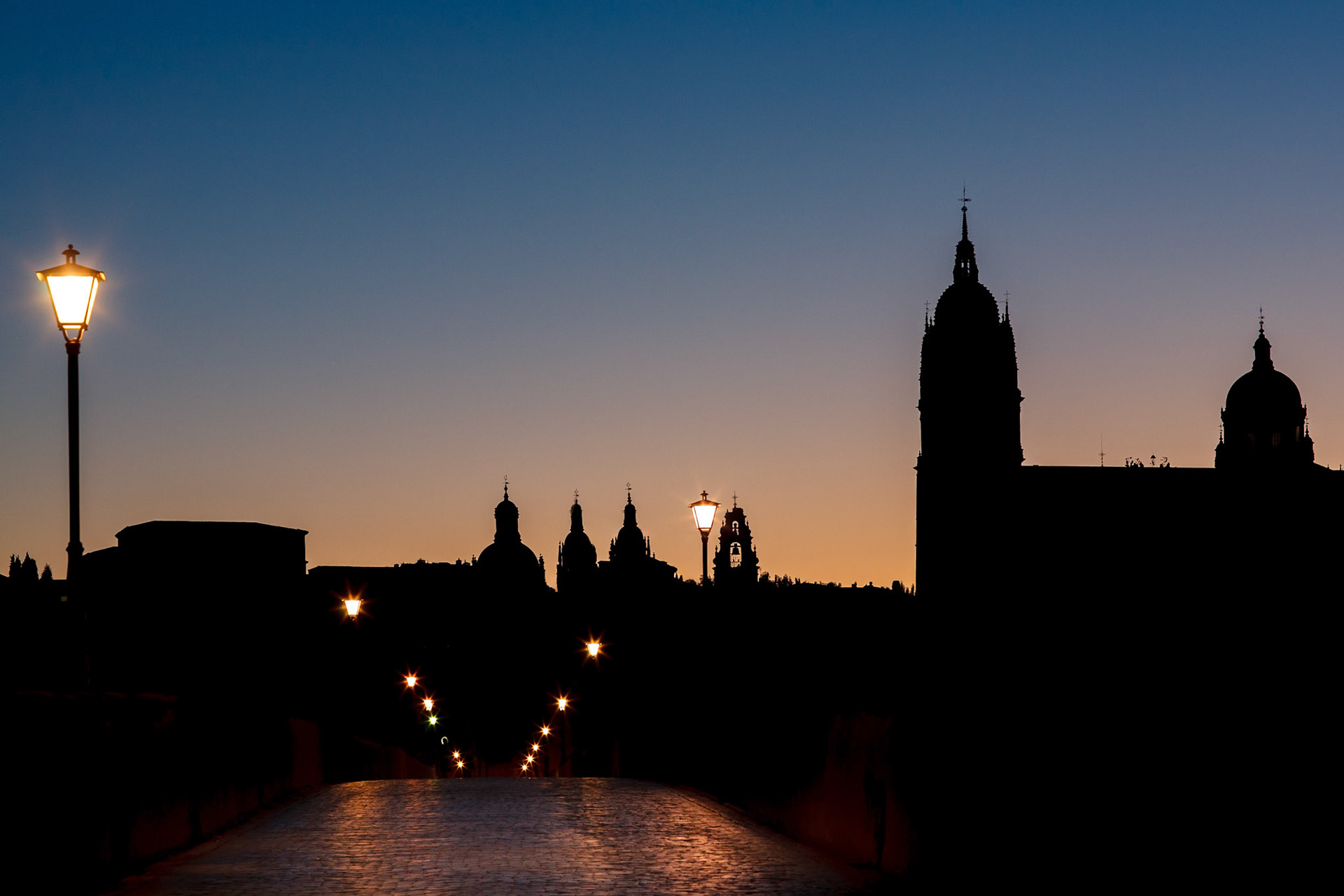 Silhouette of the New Cathedral and Roman Bridge during a peaceful dawn in Salamanca.