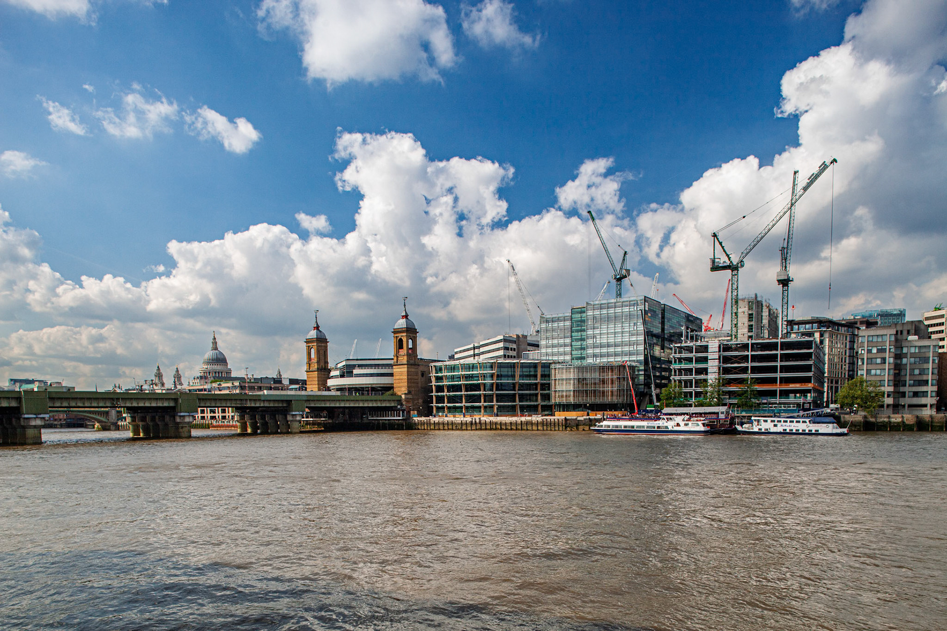 Construction work takes place on new buildings beside the River Thames and Cannon Street Railway Bridge in London during the year 2009.