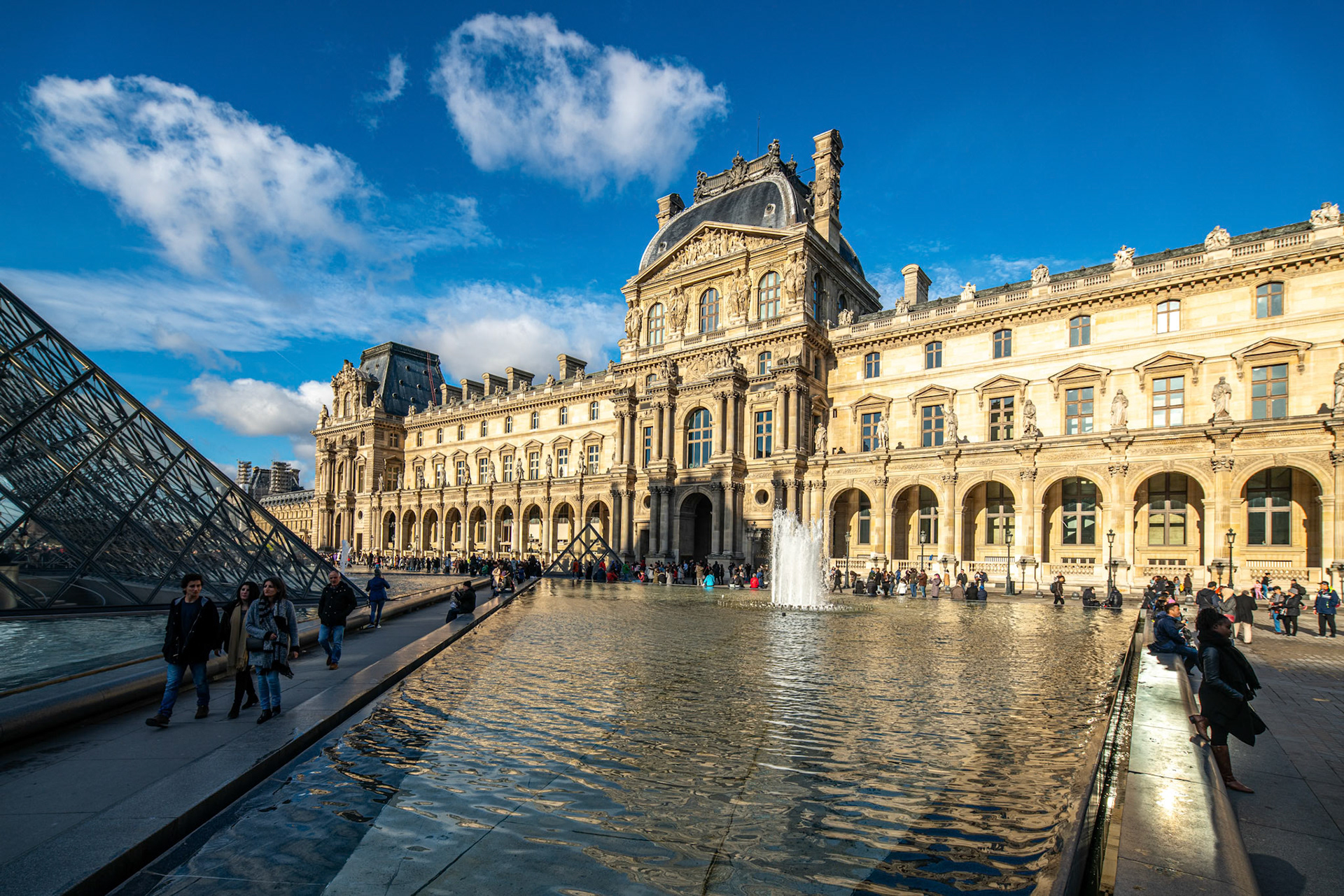 Visitors walking near the Palais Royal under a clear blue sky.