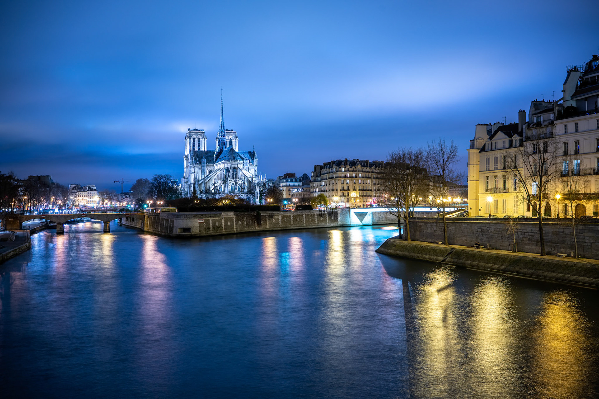 Twilight casts a glow over Notre Dame and Île de la Cité, seen from Pont de la Tournelle against a vibrant Paris sky.