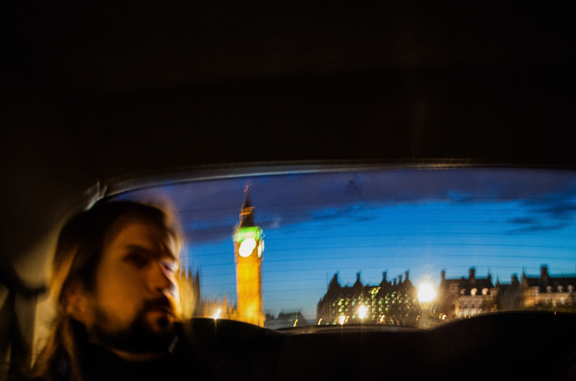 Passenger reflecting in a taxi window against the backdrop of illuminated Big Ben.