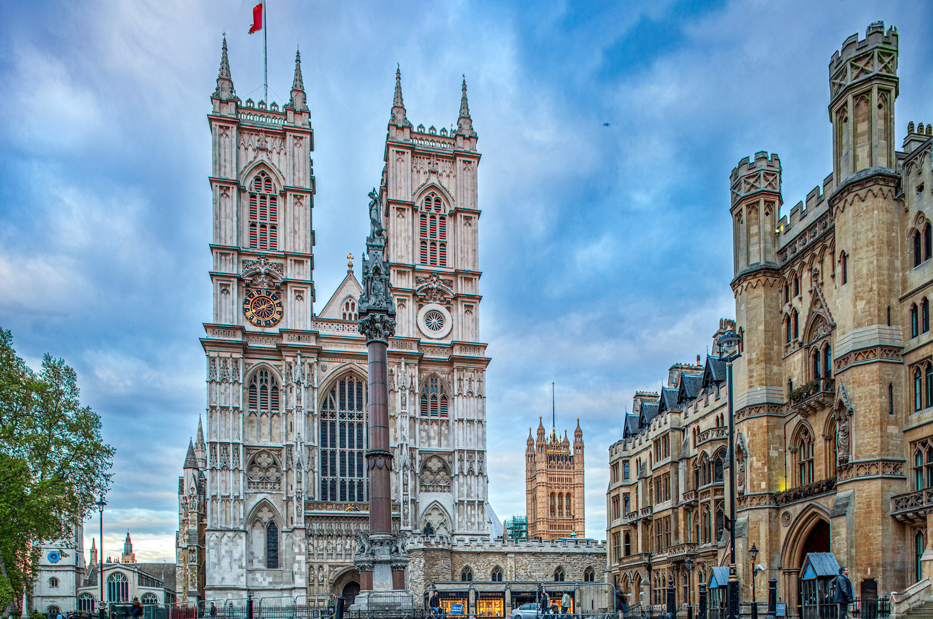 Westminster Abbey stands beside the Broad Sanctuary building under a cloudy evening sky.
