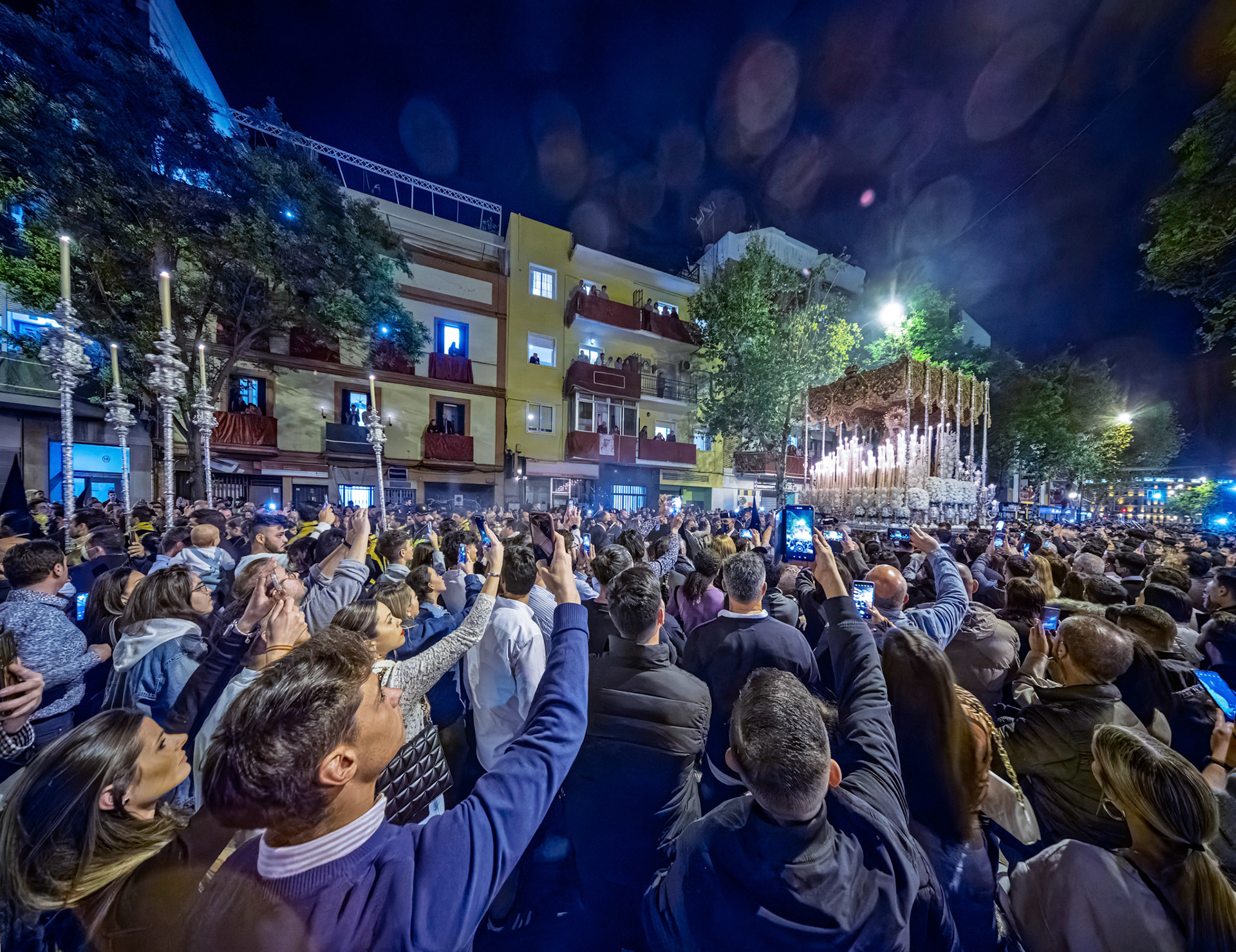 Vast crowd fills Resolana Street in Seville during the early hours of Good Friday. Spectators watch the Esperanza Macarena palio procession for Holy Week.