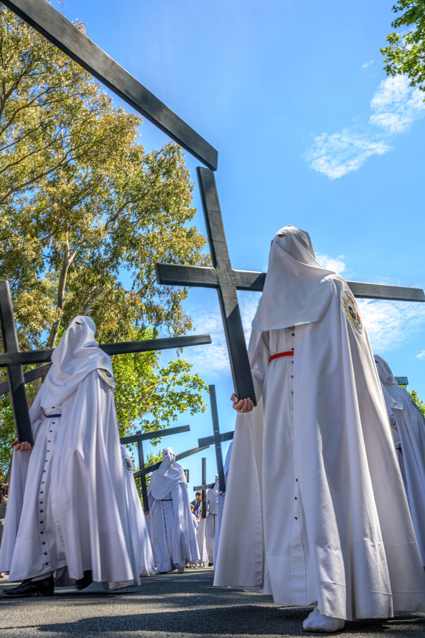 Nazarenos of Seville's Paz Brotherhood carry wooden crosses in penitence during the Palm Sunday procession of Holy Week, Andalusia, Spain. A solemn tradition.