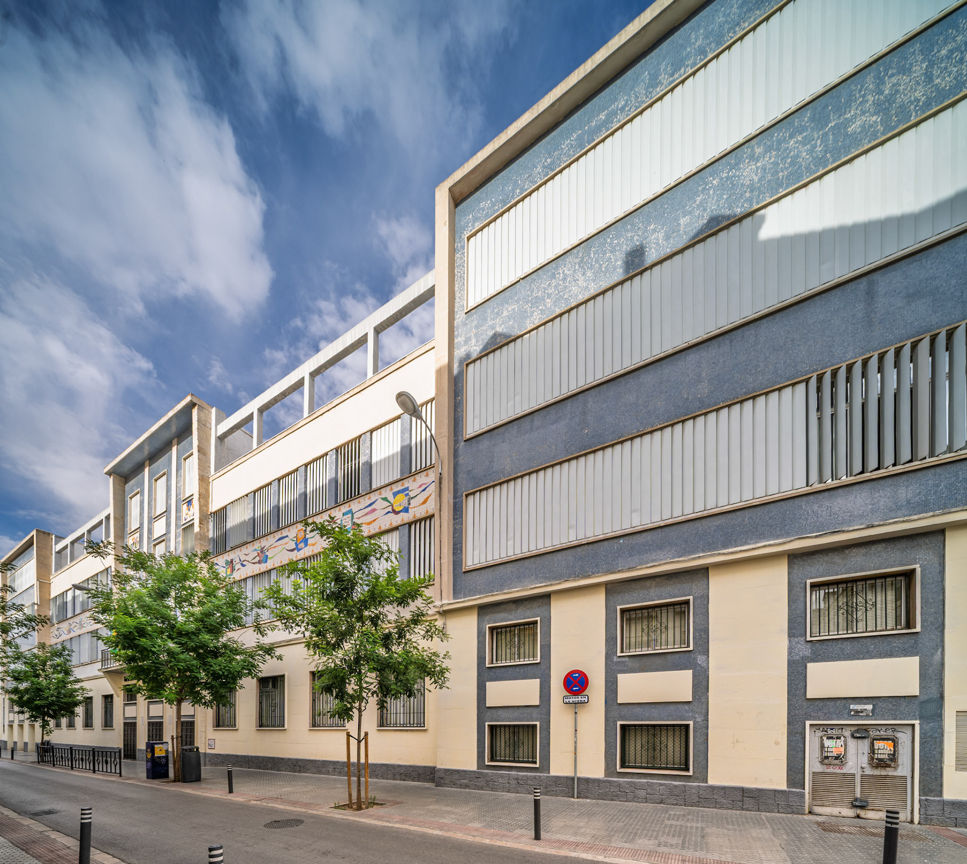 Instituto San Isidoro stands as Seville's first public secondary school, showcasing its rationalist architecture from the 1960s along a sunny street.