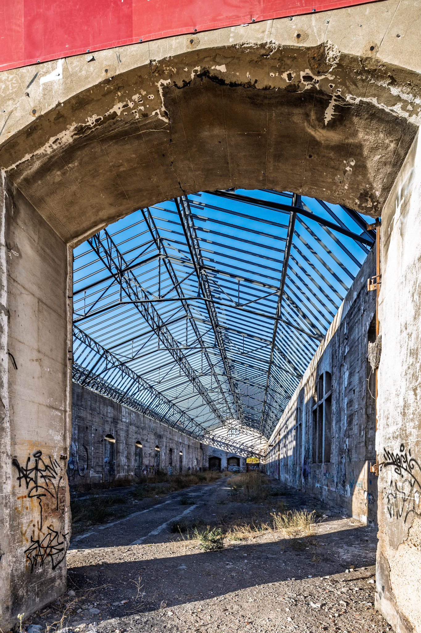 Renfe's San Jerónimo warehouses feature graffiti-covered walls and skeletal steel trusses, revealing their history before the 2023 renovation.
