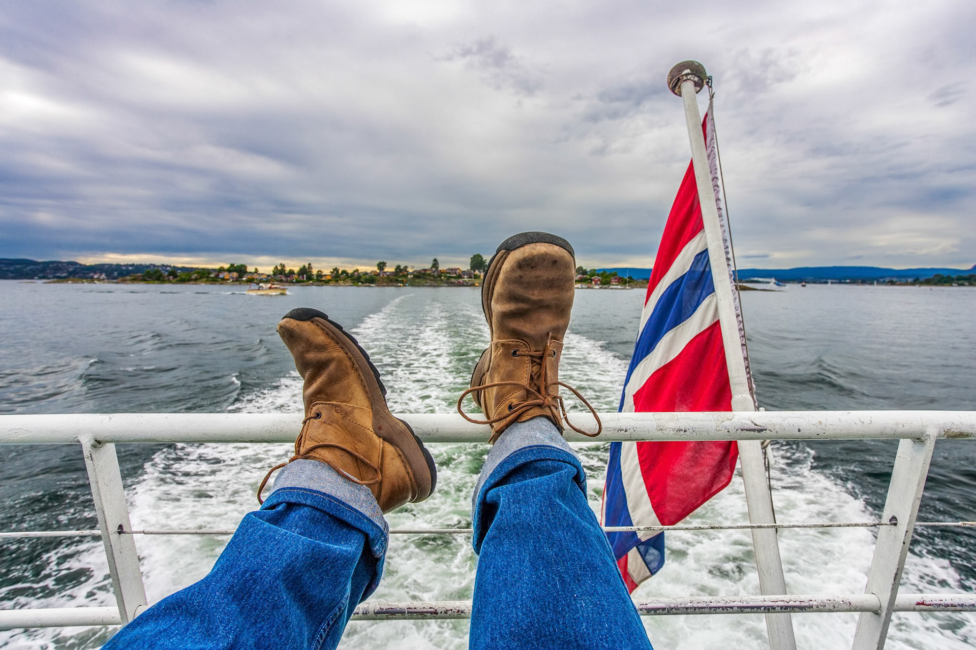 Feet on a boat railing, cruising Oslo's calm waters—capturing pure relaxation in Norway's stunning scenery.