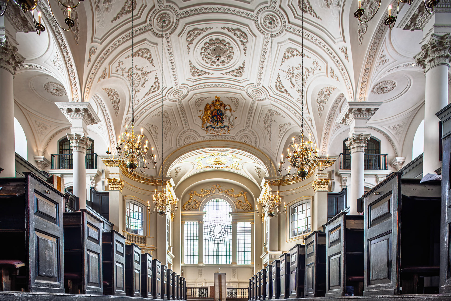 Visitors can see ornate details and wooden pews inside Saint Martin in the Fields church in London. The architecture is grand and historic.