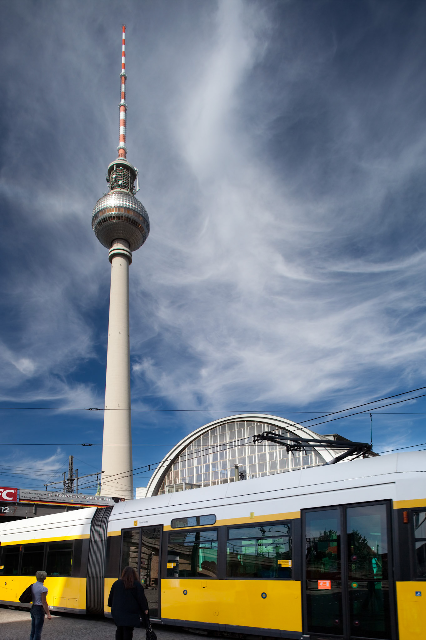 A tram travels through Alexanderplatz, showcasing the iconic Fernsehturm and vibrant urban life in Berlin, Germany.