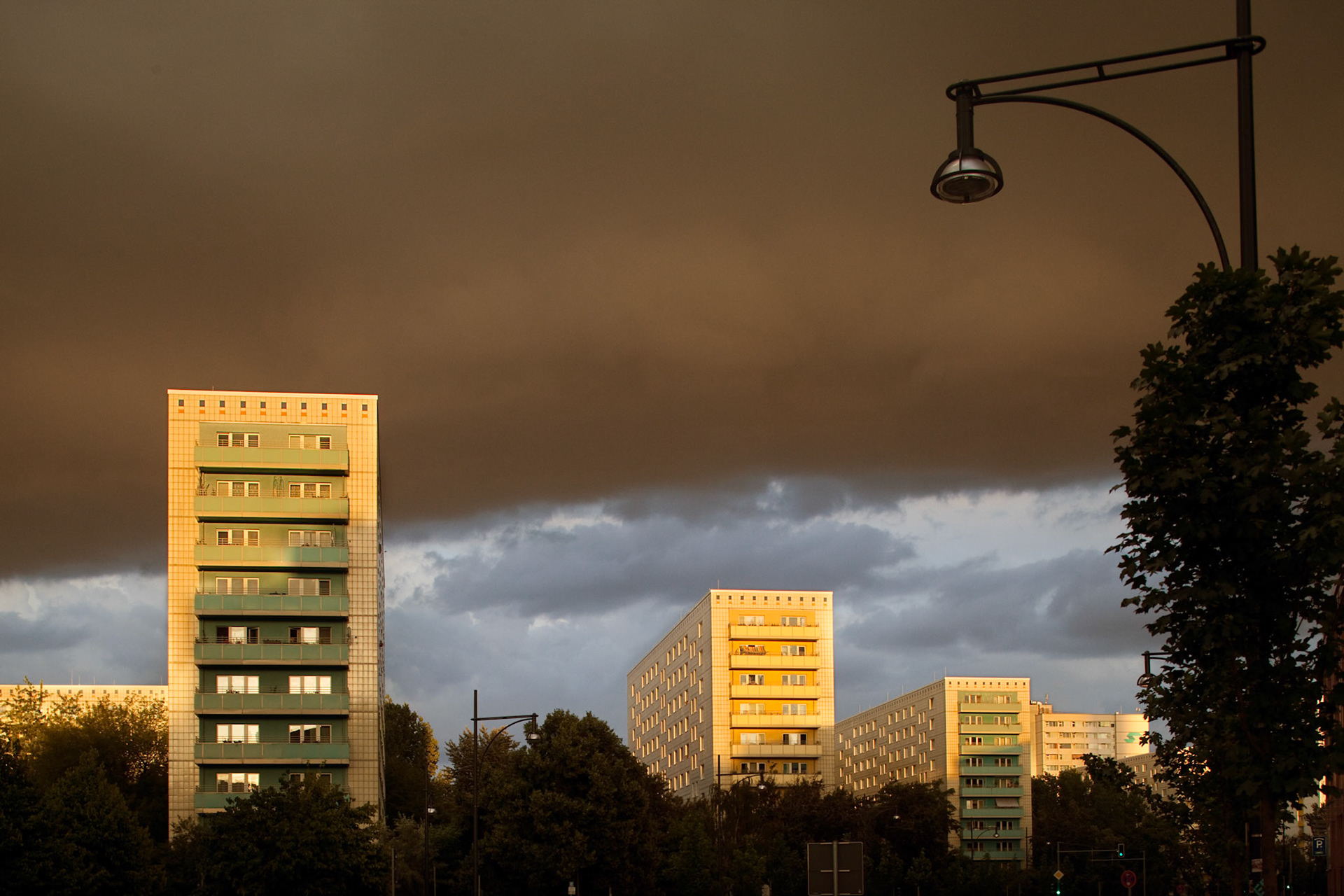 The striking apartment buildings on Alexander Street glow in the evening light against a dramatic sky in East Berlin.