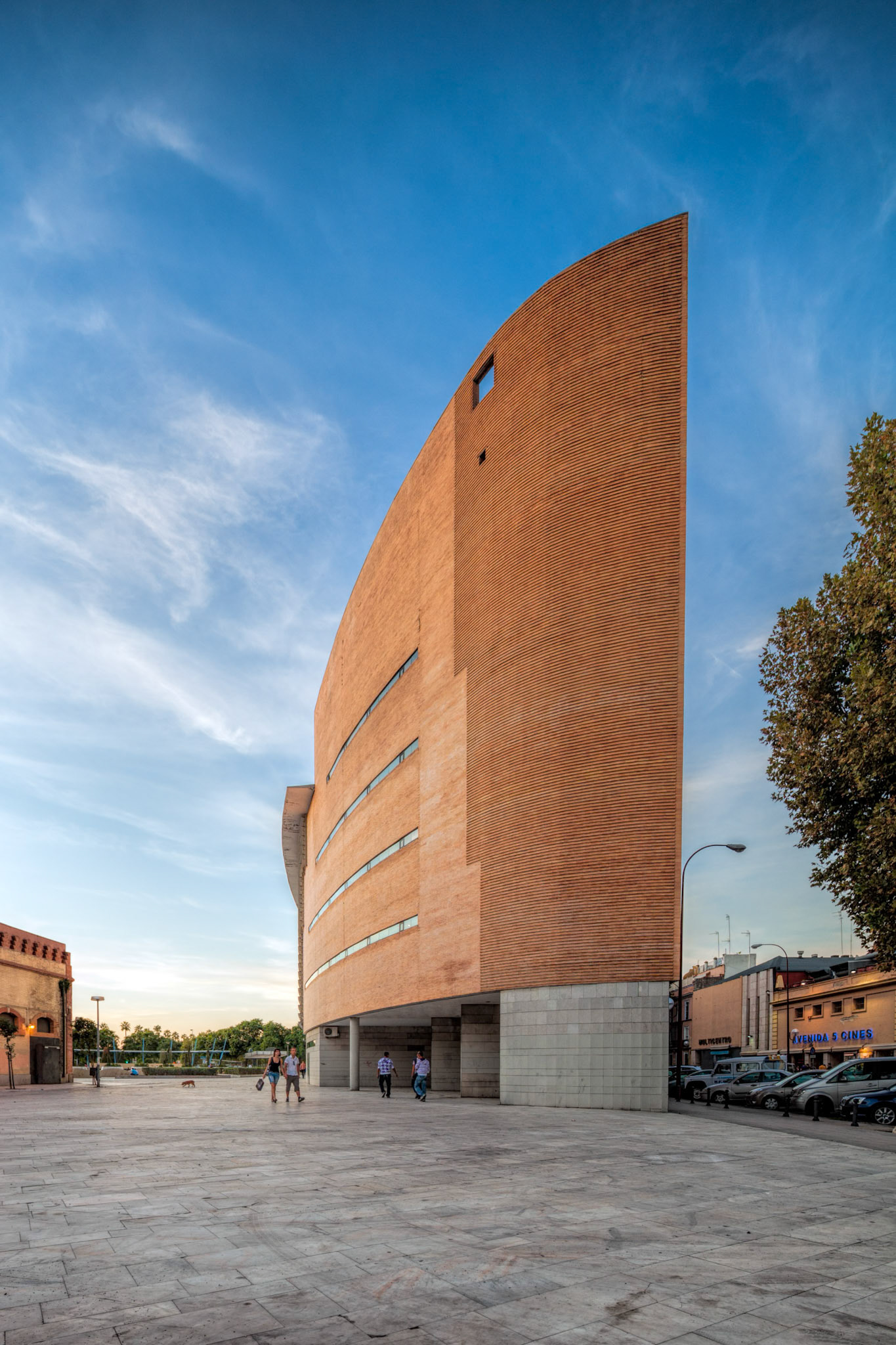 Seville, Spain, Sep 30 2009, A sleek contemporary building stands tall in Seville, Spain, surrounded by beautiful evening light as people stroll by in the plaza.