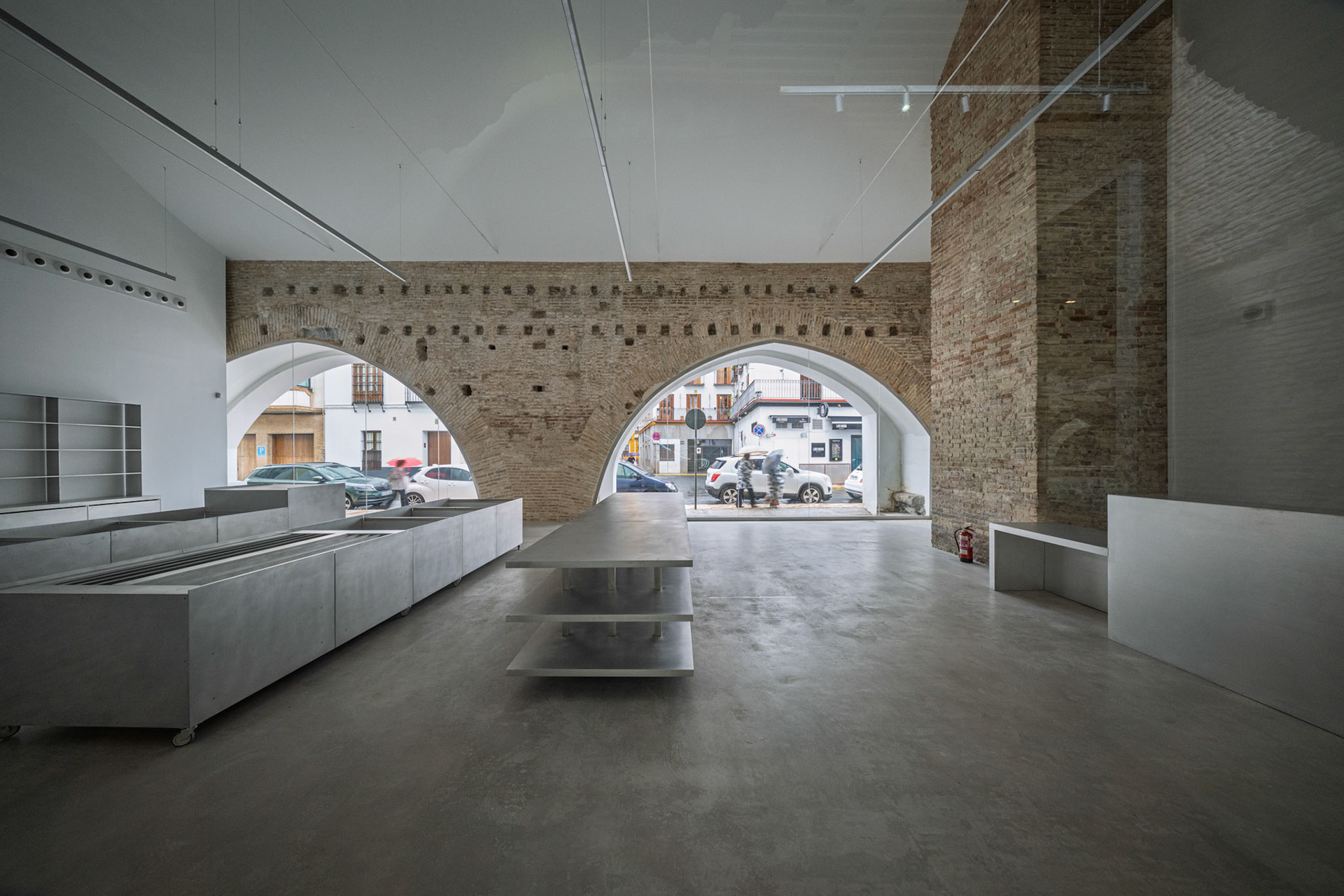 This stylish Seville dining area boasts arched brick openings, modern counters, and street views, merging history with contemporary design.