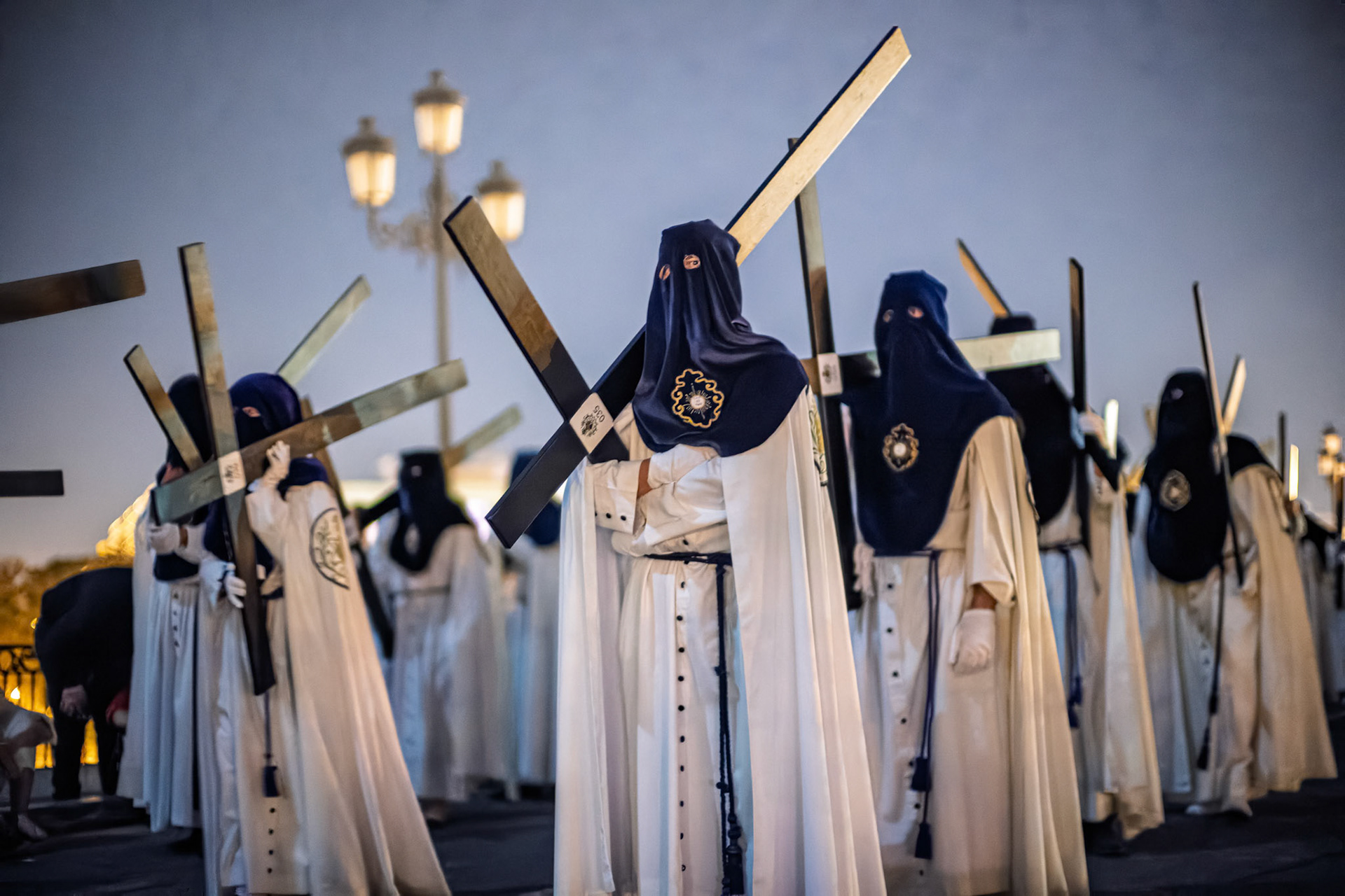 Narazenos de la Estrella members carry wooden crosses as penance during the Palm Sunday night procession of Holy Week in Seville, Andalusia, Spain.