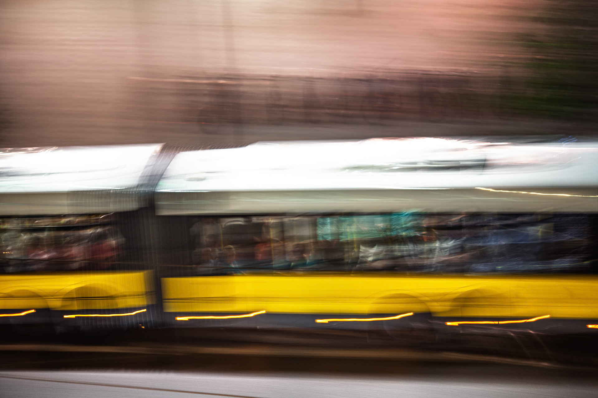 A tram travels swiftly along the streets of Berlin, illuminated by city lights at night, creating a vibrant and dynamic scene in the urban landscape.