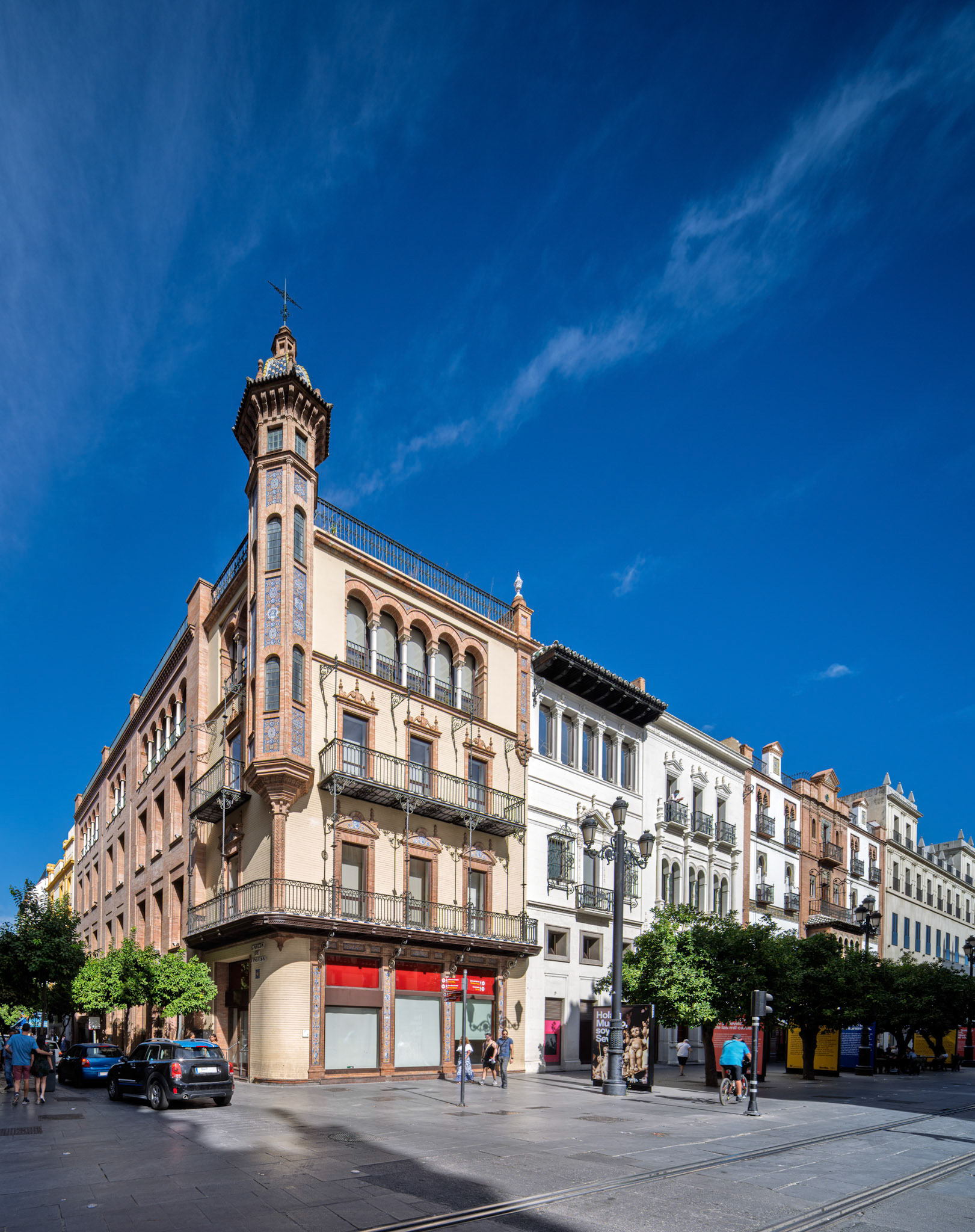 Seville—Álvaro Dávila’s house by Aníbal González (1915–1917), on Avenida de la Constitución, blends neoplateresque and neomudéjar styles with brick, ironwork, and glazed tile.