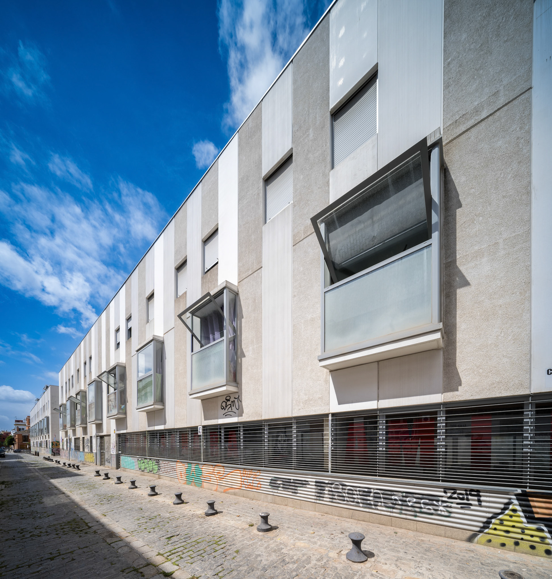 Urban social housing structure in Seville, Spain, surrounded by decorated city streets.