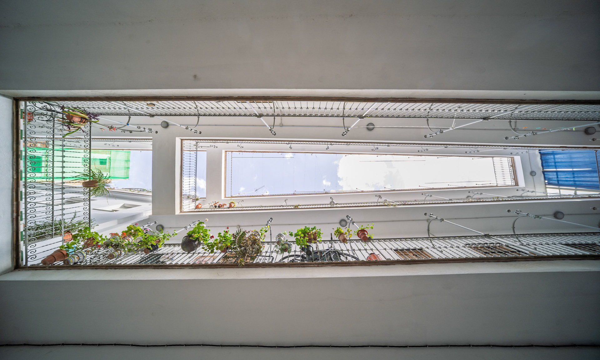 Pasaje Valvanera, seen from below—courtyard balconies rise in stacked symmetry, with potted plants and open sky framing this 1915 social housing by Manuel Martín.