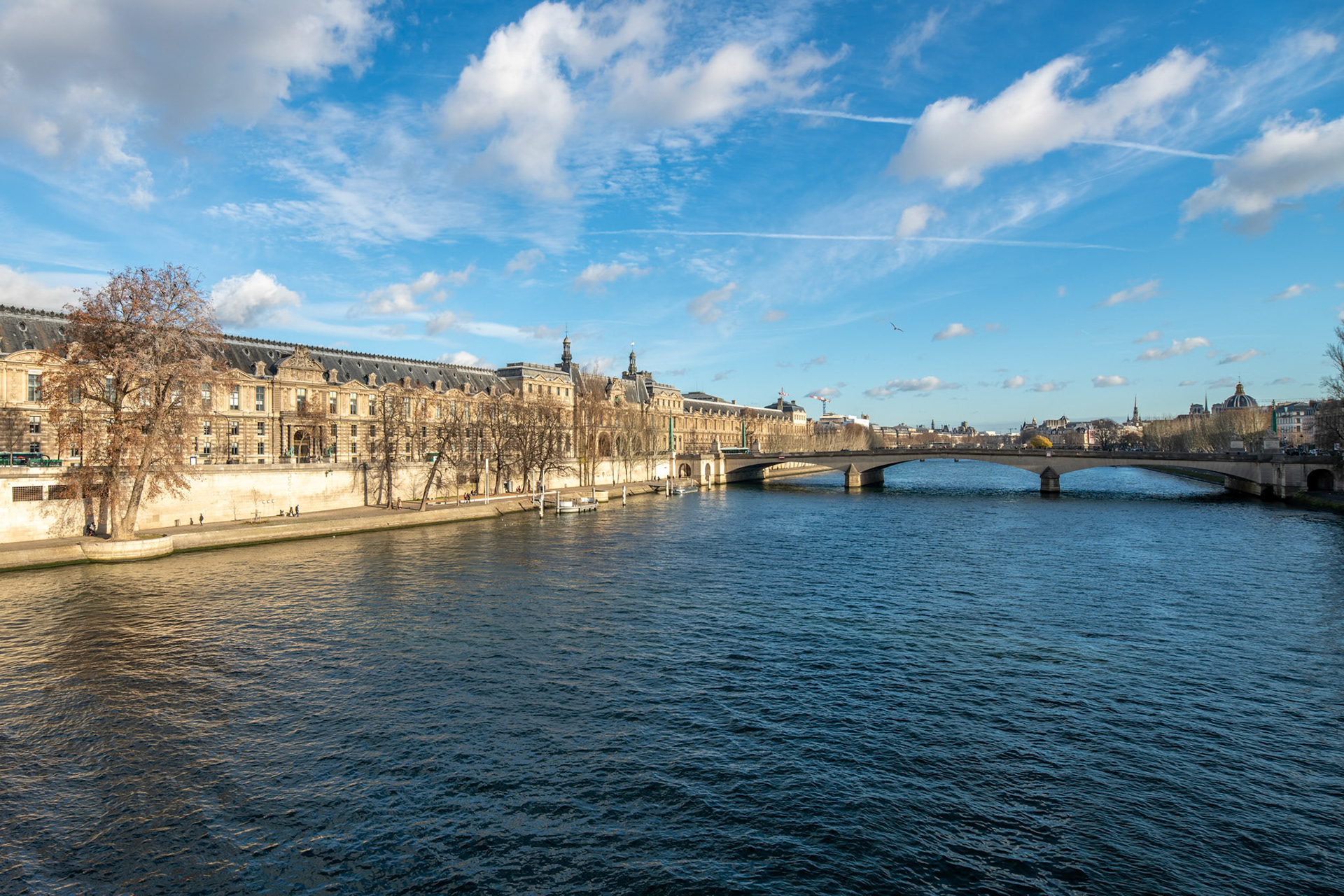 Clear skies over the Seine with a view of the Louvre and Pont du Carrousel.
