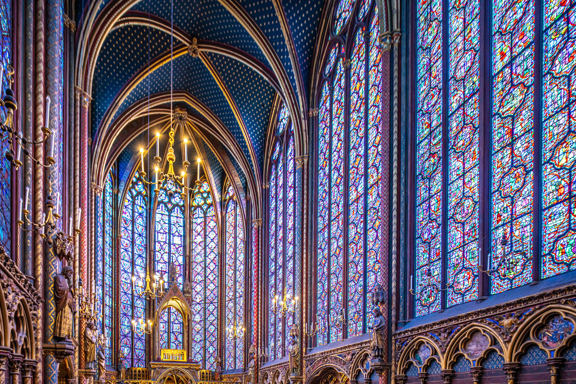 Vaulted ceiling and stained glass windows of Sainte Chapelle, Paris bathed in colorful light.