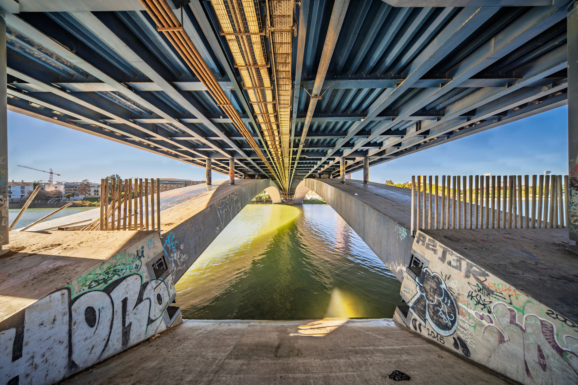 Exploring the underside of Cristo de la Expiracion Bridge reveals steel beams, infrastructure, and colorful graffiti.
