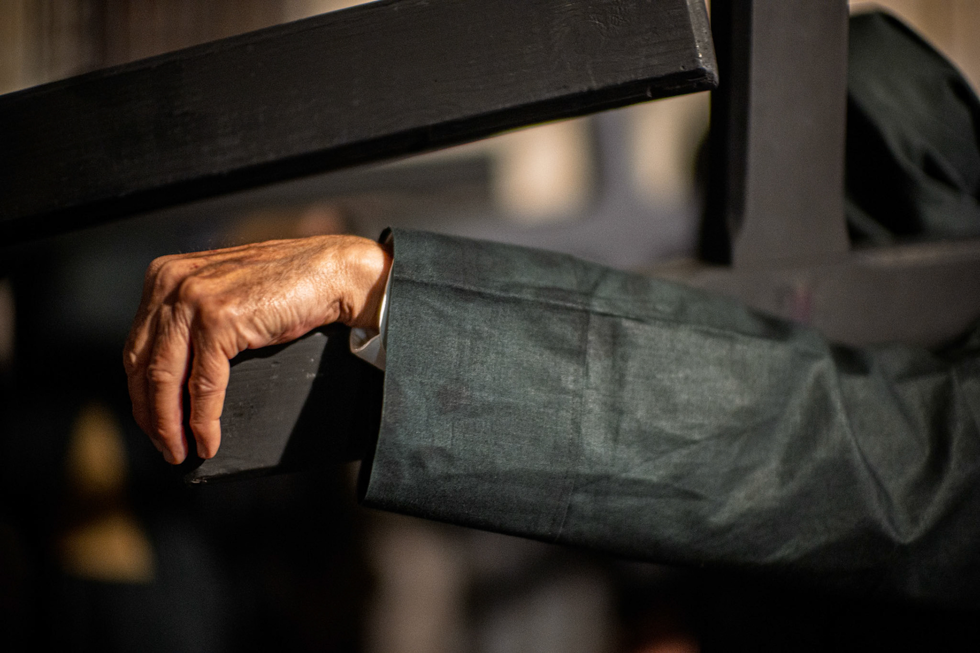 Detail of an Estudiantes Brotherhood Nazarene's hand and arm carrying a penitential cross during the Holy Tuesday procession in Seville, Holy Week.