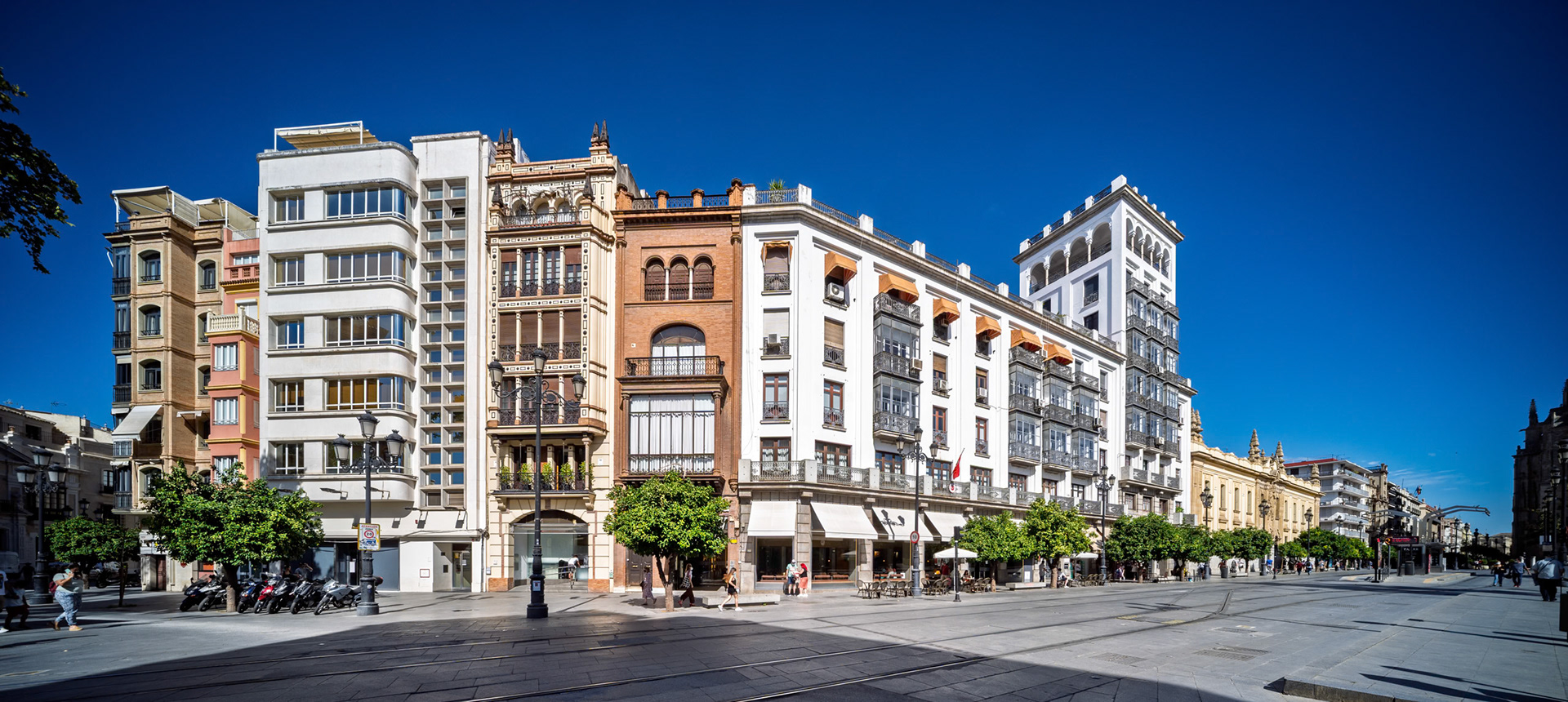 Avenida de la Constitución, Seville—rationalist building by Galnares Sagastizábal &amp; Wespi Schneider (1936) anchors the row, followed by La Aurora (Illanes del Río, 1933) and Correos (Lozano &amp; Otamendi, 1927–30), blending modernist and eclectic civic styles.