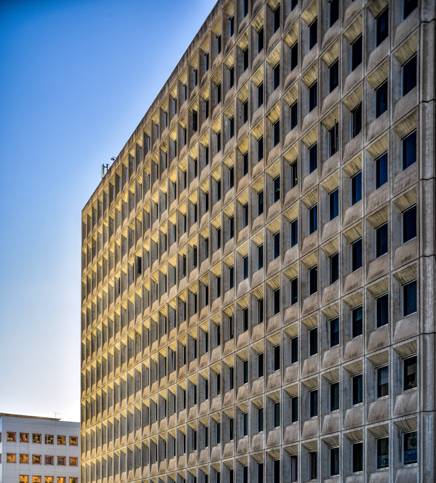 Close-up view of the rationalist style Edificio Sevilla 1, built in 1972, in Seville, Andalusia, Spain. The facade shows repetitive window patterns.