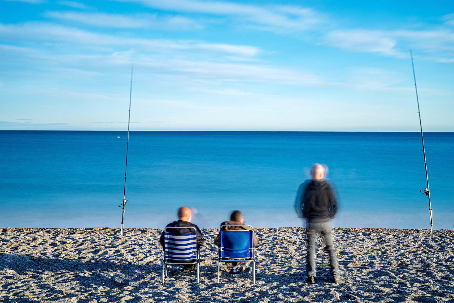 Fishermen enjoy a peaceful day fishing off the Granada coast of Spain. Long exposure creates a soft, dreamy seascape. Serene and relaxing.