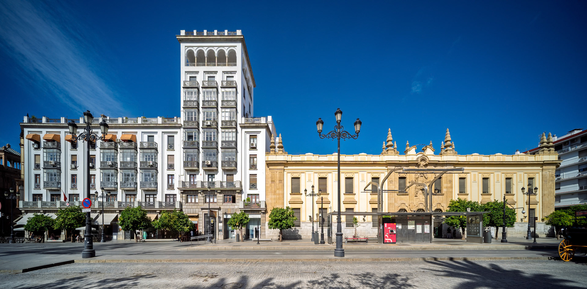 Avenida de la Constitución, Seville—Correos (Lozano &amp; Otamendi, 1927–30) and La Aurora (Illanes del Río, 1933) face the pedestrian boulevard with civic elegance and early 20th-century flair.