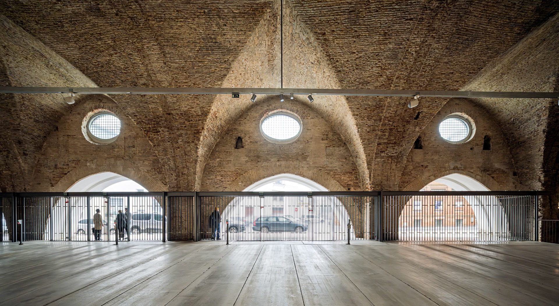 The restored Atarazanas in Seville showcases original brick vaults and circular windows, allowing natural light to fill the historic shipyard space.