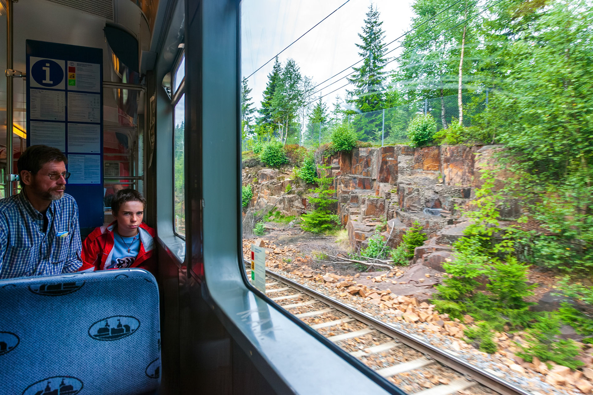 Oslo, Norway, Aug 10 2017, Passengers relax on a suburban train in Oslo while scenic greenery and rocky landscapes pass by the window on a cloudy day.