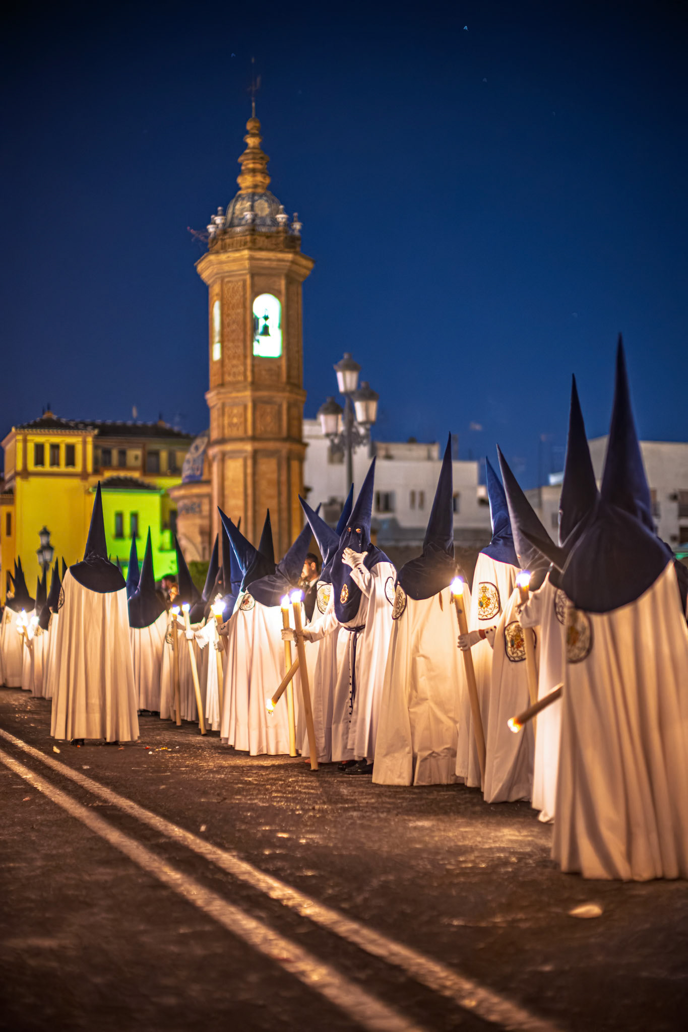 Estrella Brotherhood Nazarenes process by Carmen Chapel on Triana Bridge during Holy Week in Seville, Andalusia, Spain, on Palm Sunday night.