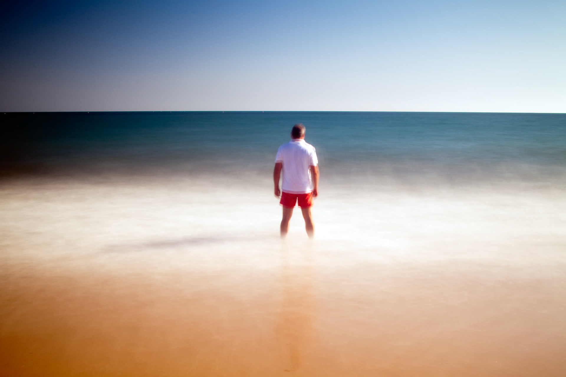 Man on a beach staring at the sea. Daylight long exposure shot by the use of neutral density filters. Model release available.