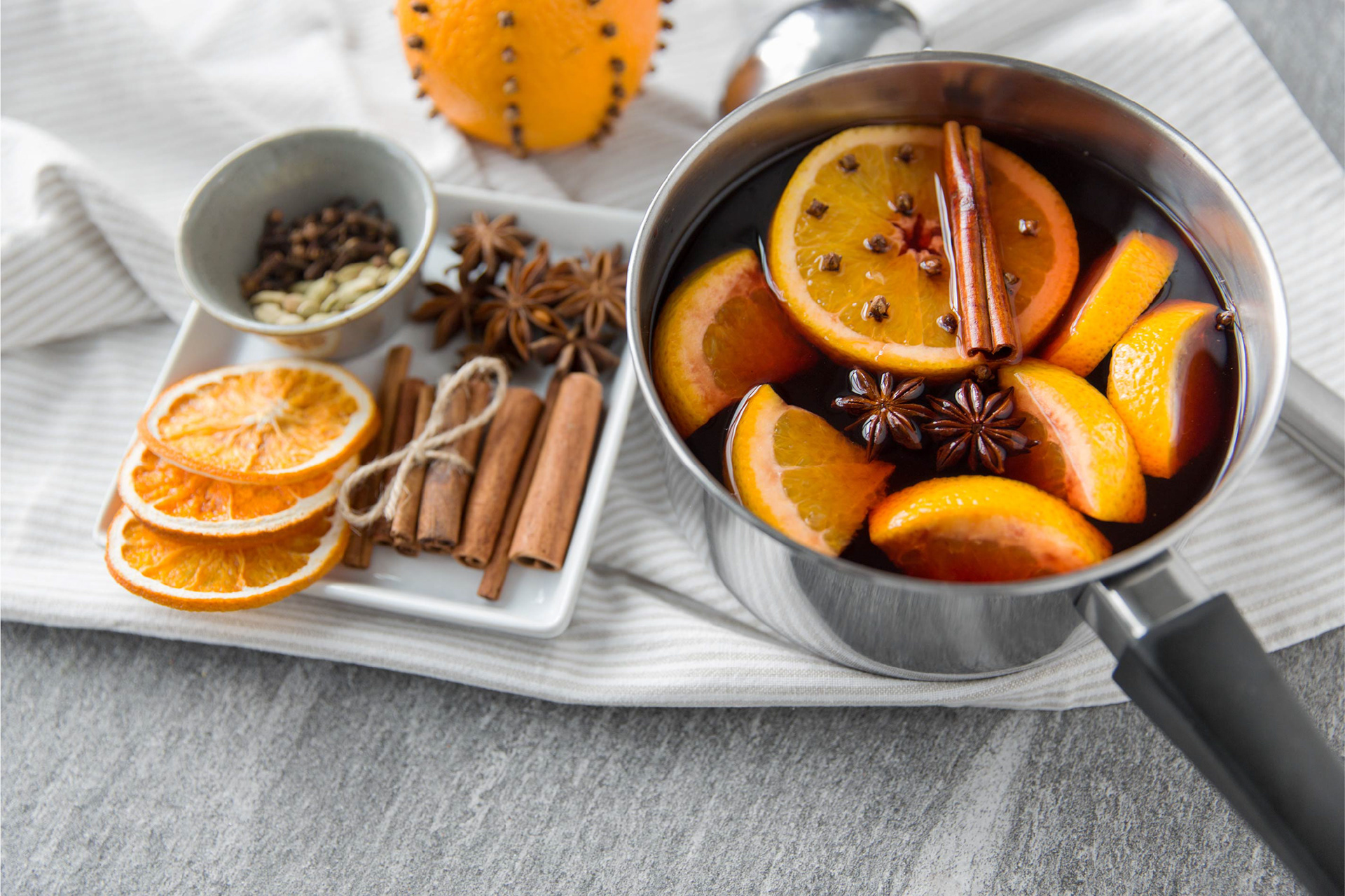 Mulled wine in pot with ingredients next to it