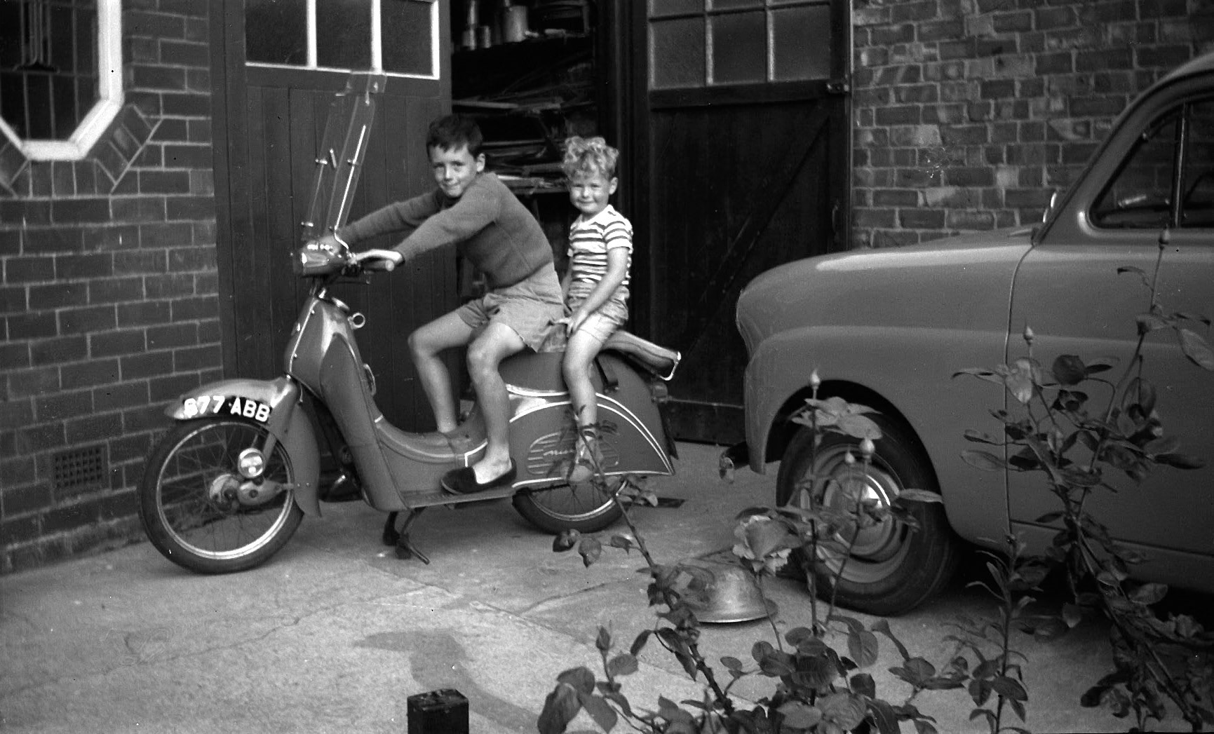 Stuart and Howard on Frank’s motor scooter. Note army helmet and Standard 8 car.