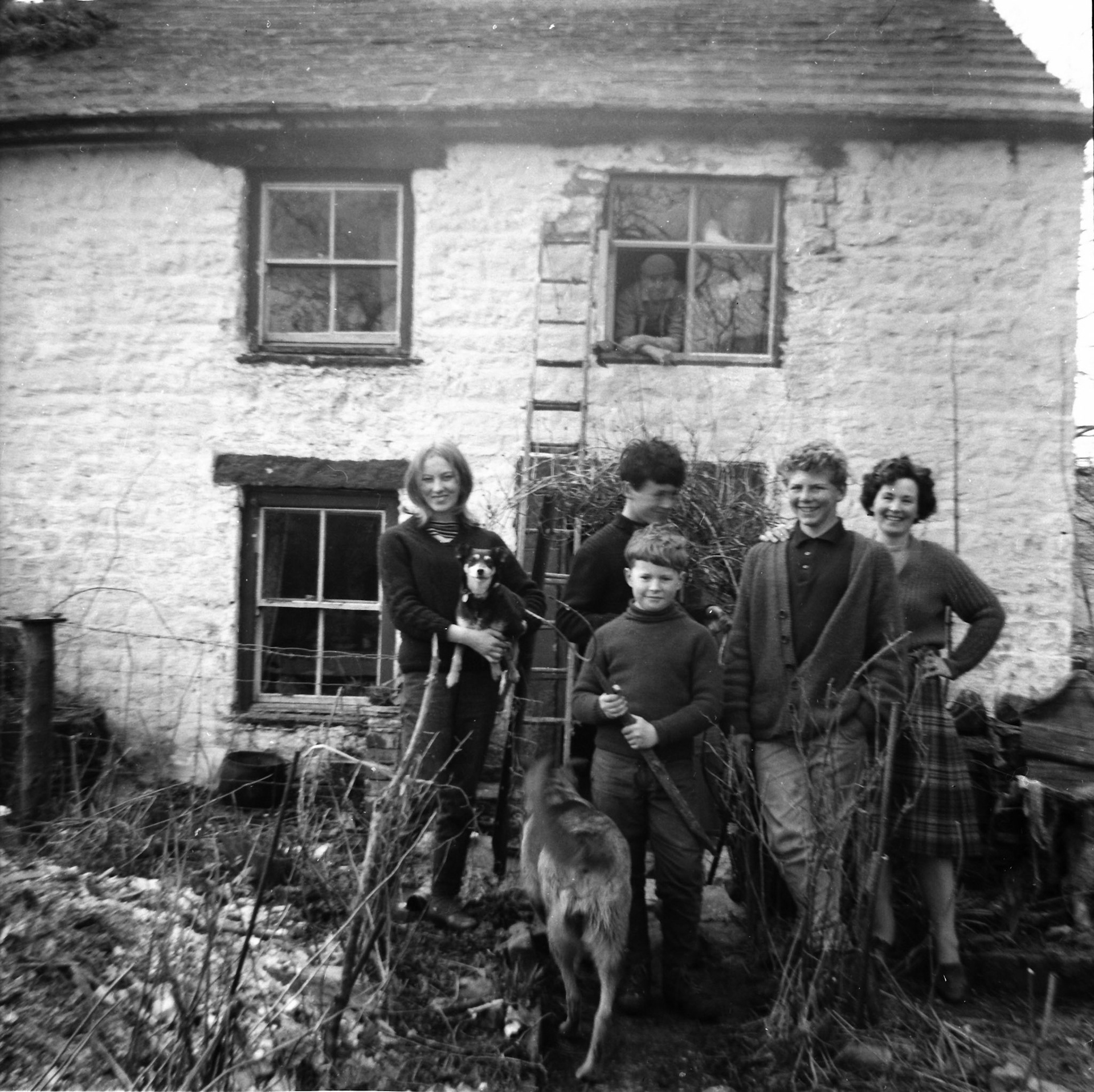 "1964 Lesley Wright, Midge, Beauty, Stuart, Paul Beverely, Irene and Frank leaning from the new window he was putting in" Sam Wright in window.