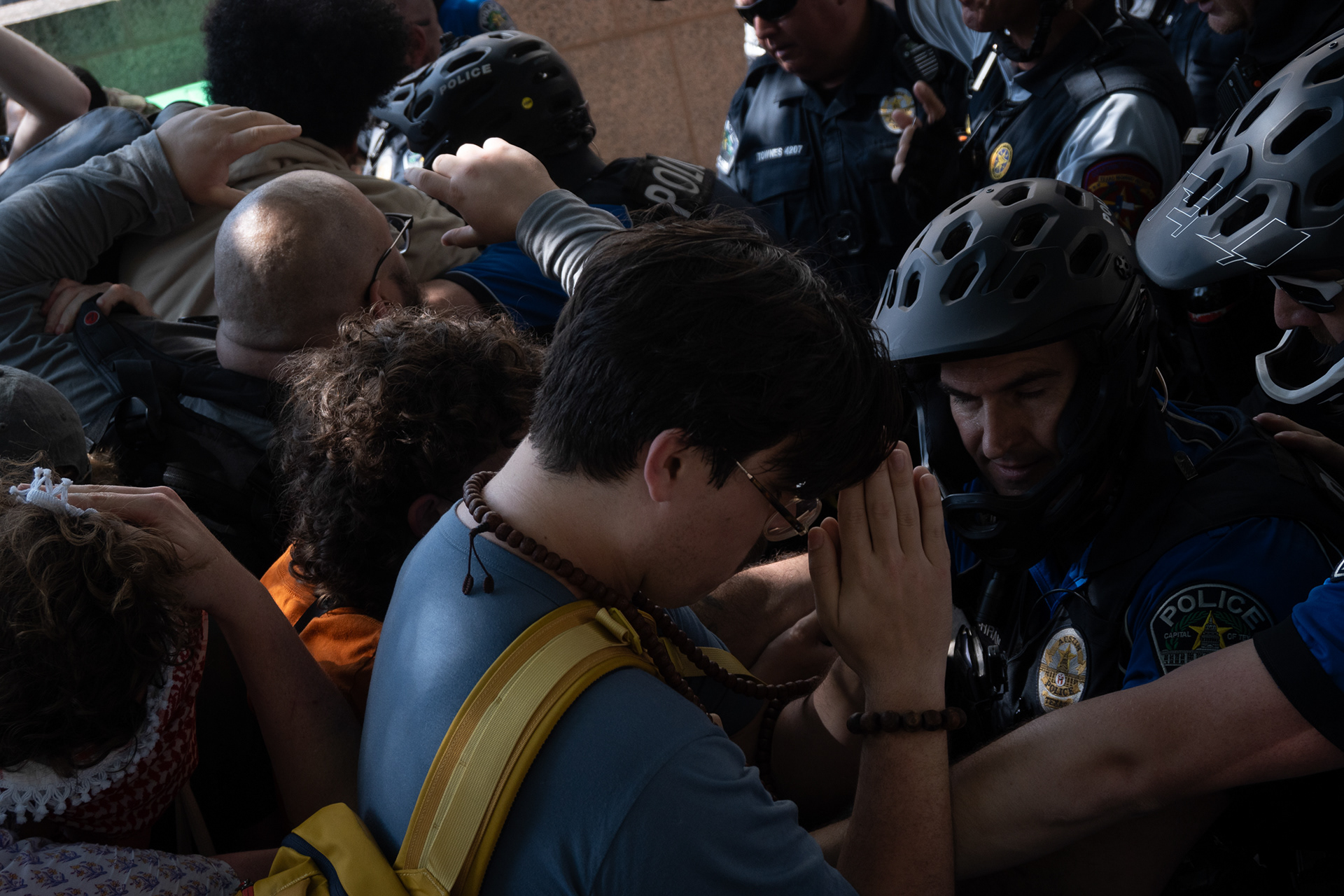 A pro-Palestine demonstrator appears to pray as police push into the crowd of people following a dispersal order on the University of Texas at Austin's South Mall lawn on April 29, 2024. After participants refused to leave, they used flashbang grenades and pepper spray to disperse the crowd.