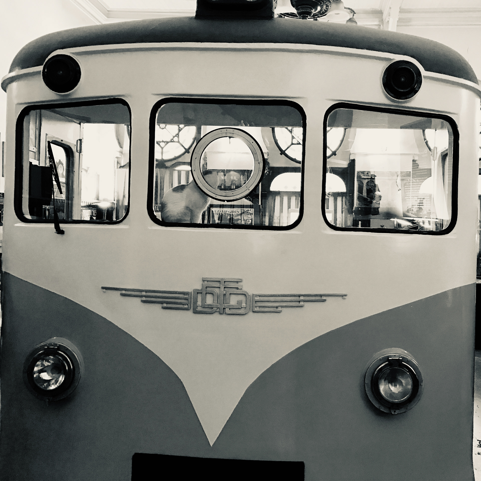 An old train engine at the Orient Express museum with a cat at the helm.