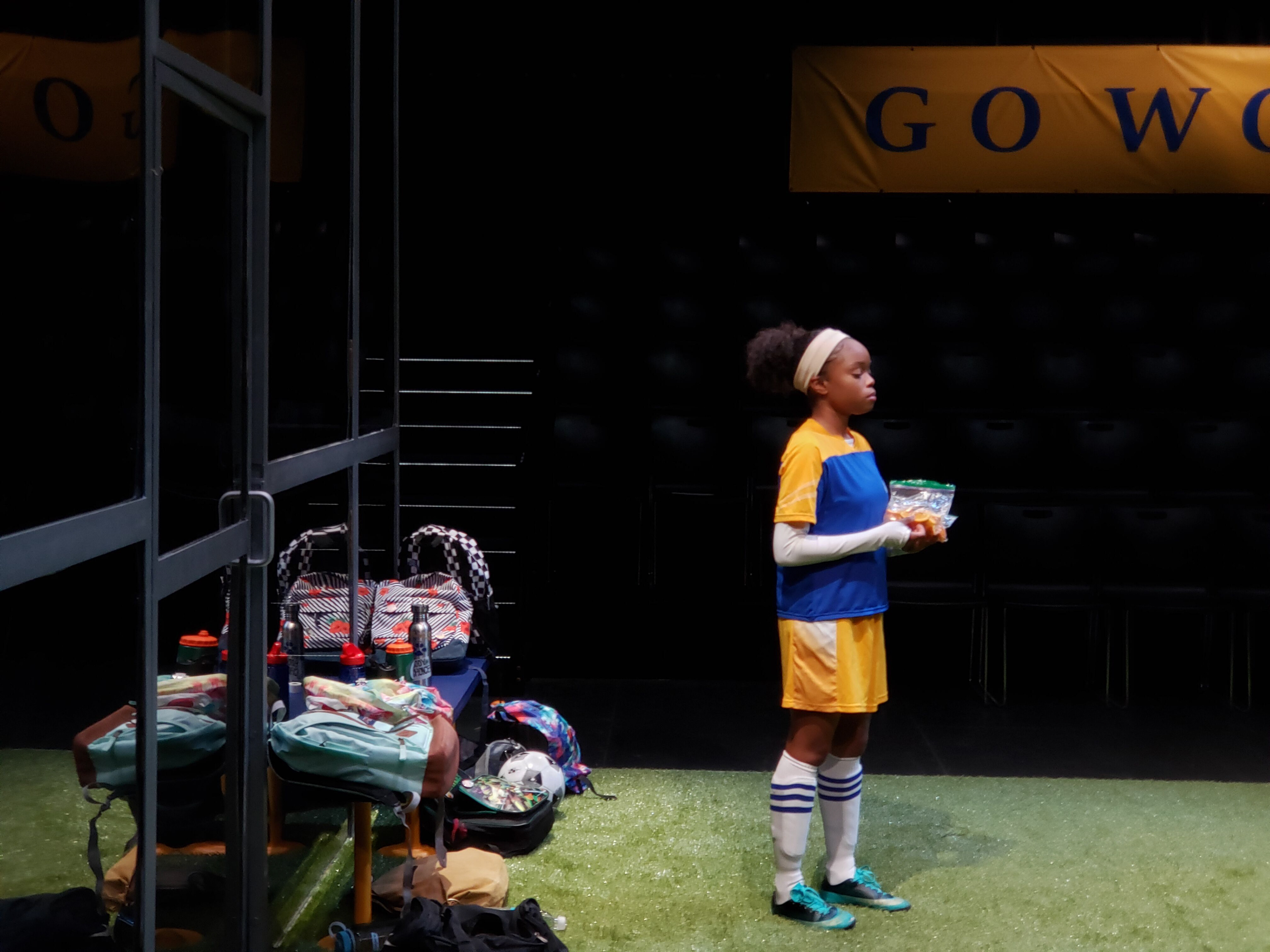 THE WOLVES SOCCER PLAYER #2 TAKING A BREAK BY THE BENCH AGAINST PLEXI WALL WITH THE GO WOLVES BANNER HANGING ABOVE AUDIENCE SEATING