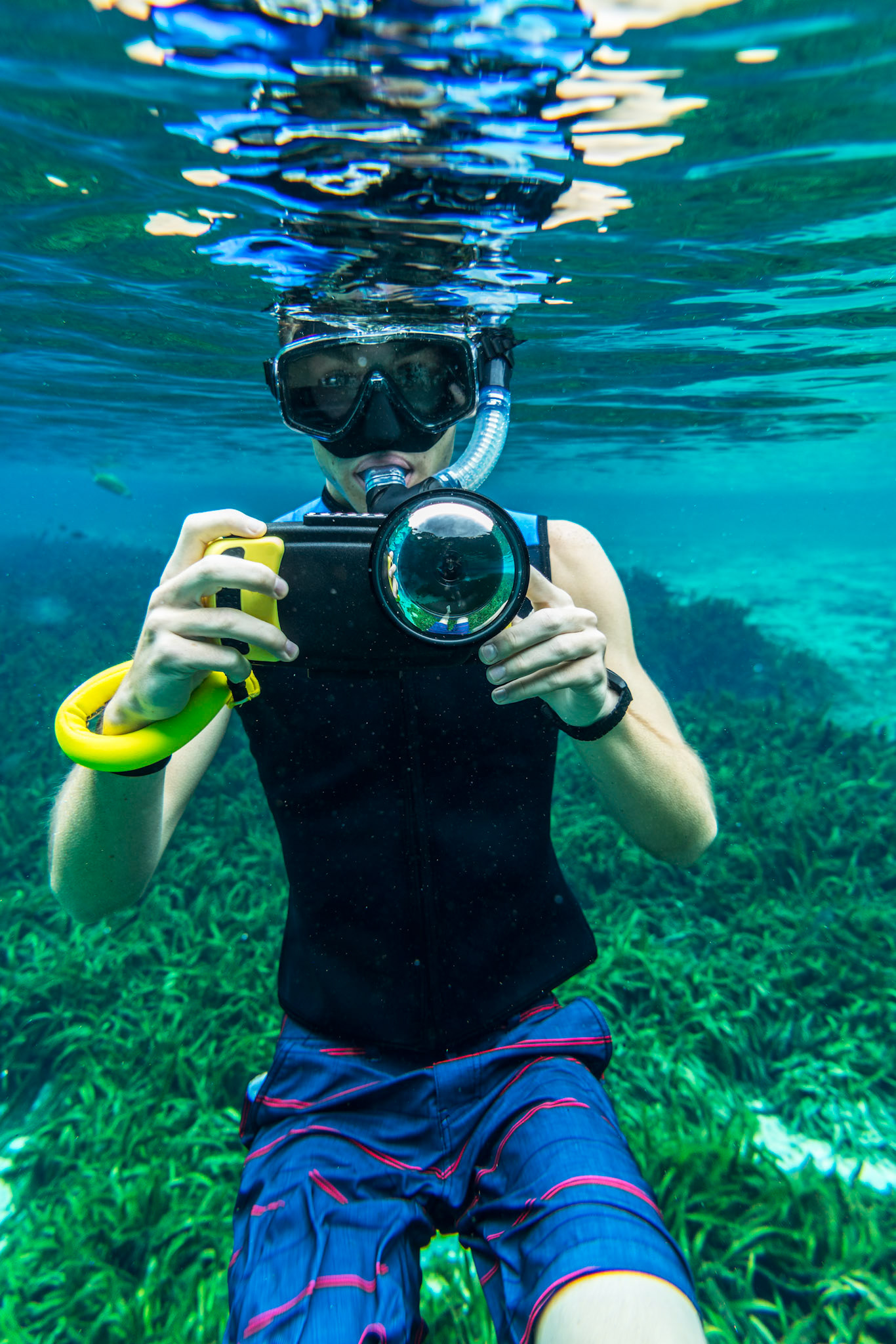 A snorkeler using a smartphone camera underwater