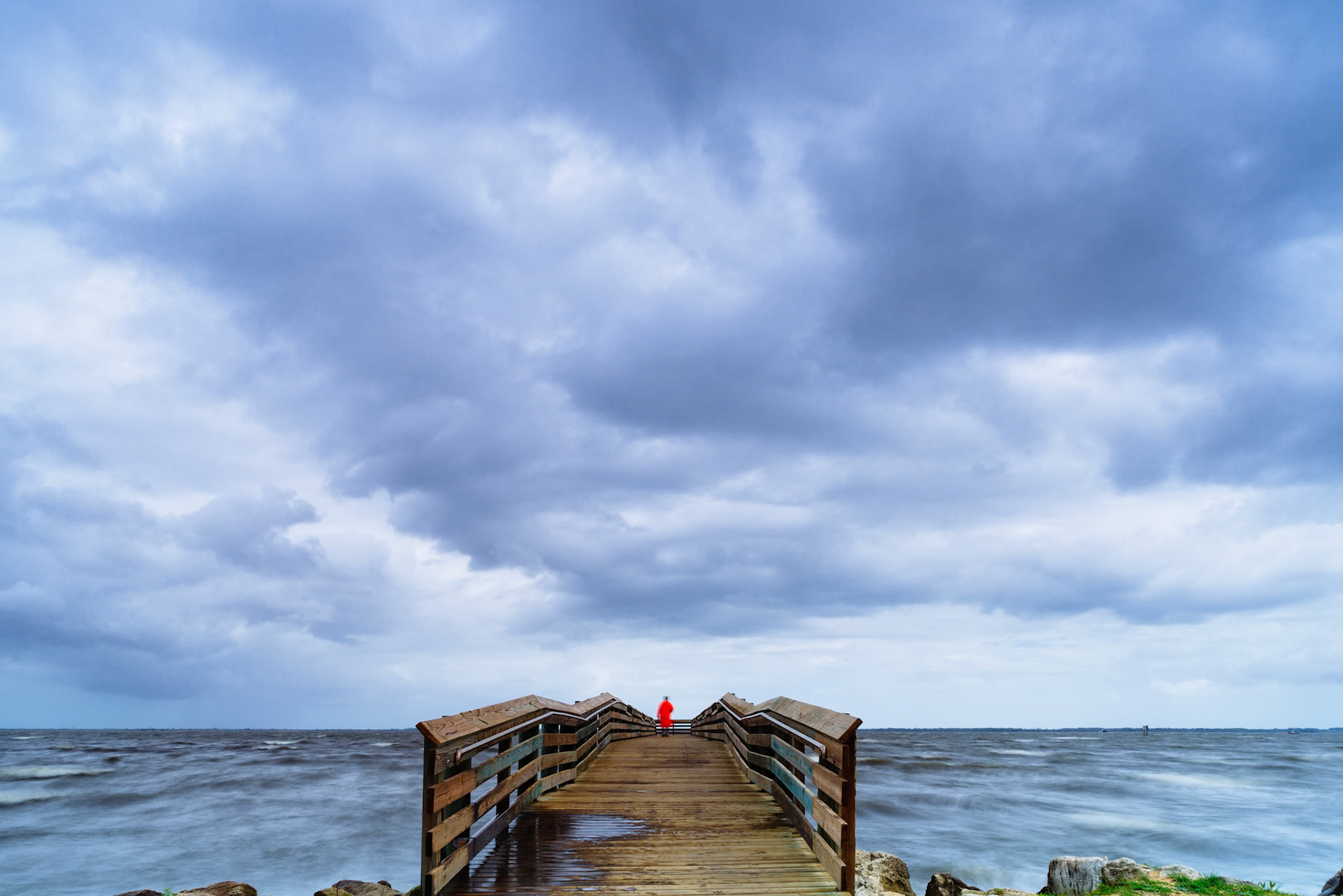 Anonymous fisherman in a bright orange raincoat
