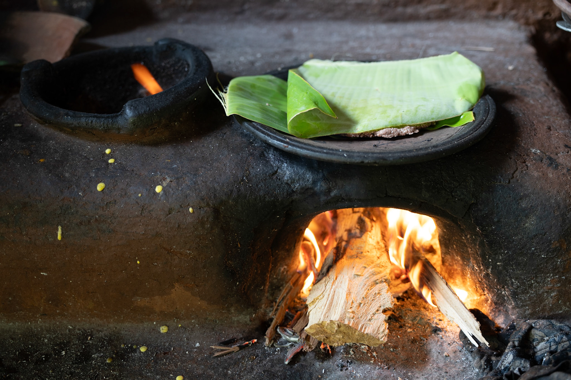 Sri Lankan wood fired oven cooking traditional food wrapped in banana leaves.