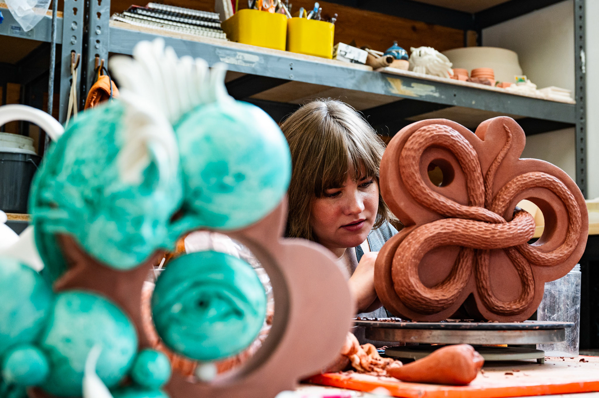 Hannah Schelb, a ceramic and sculpture artist and lecturer at the University of Wisconsin-Madison, works on her latest modular red clay sculpture during Annual Open Studio Day at the University of Wisconsin-Madison on Nov. 4, 2023. Schelb’s latest work has been motivated by personal investigations into animal dynamics and feminist rhetoric. (Photo by MK Denton / UW–Madison)