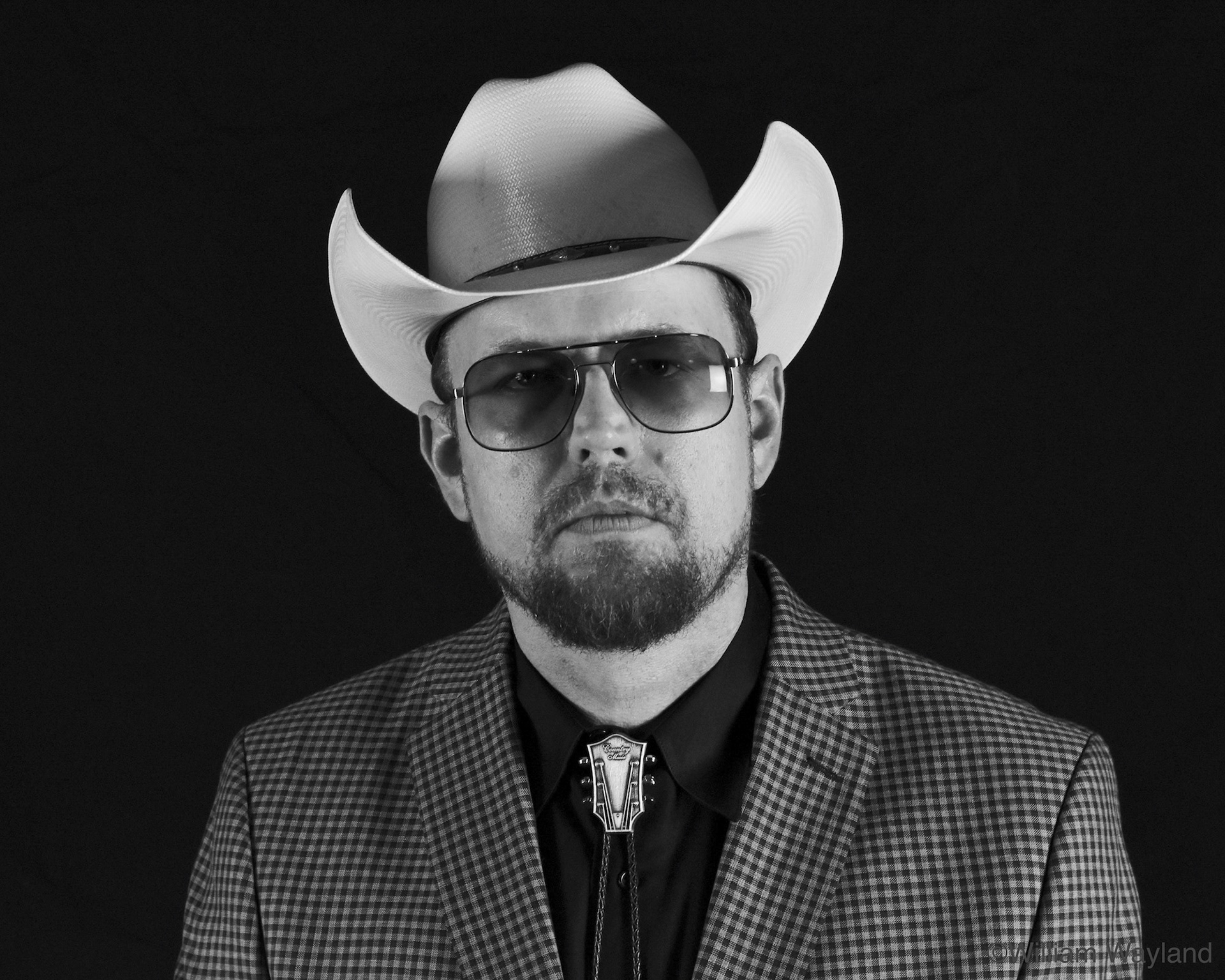 Black and white portrait of a bluegrass musician wearing a cowboy hat and glasses