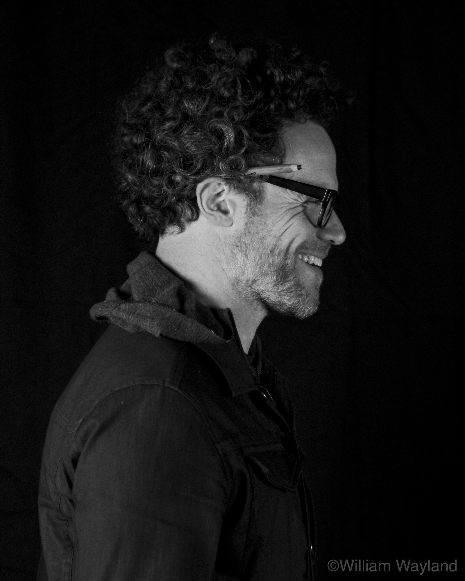 Black and white portrait of a man with glasses and a pencil
