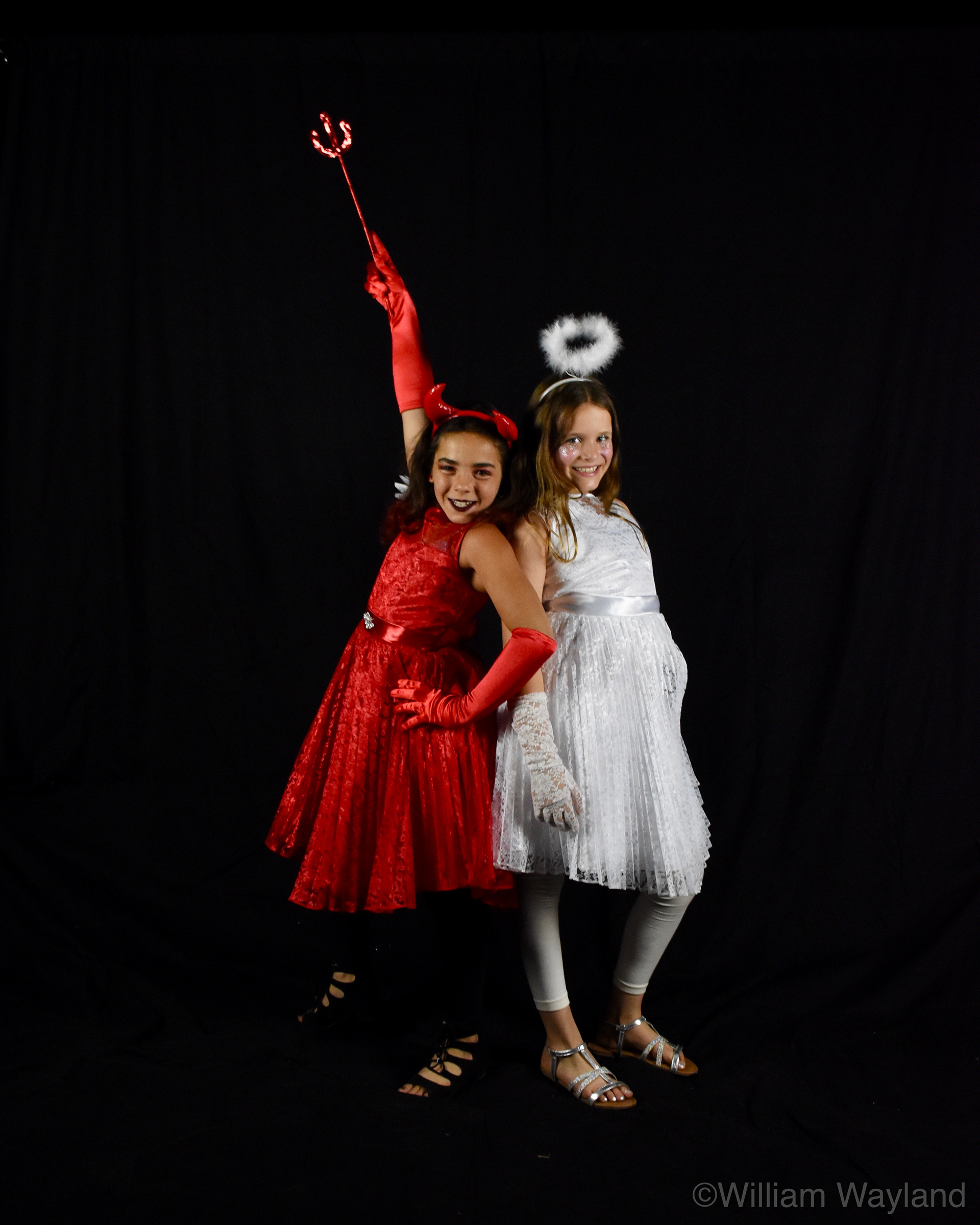 Group portrait of two girls in Halloween costumes dressed as an angel and the devil