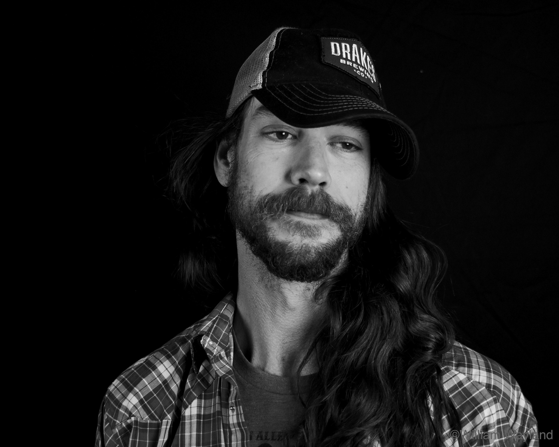Black and white portrait of a young man with a beard and baseball cap