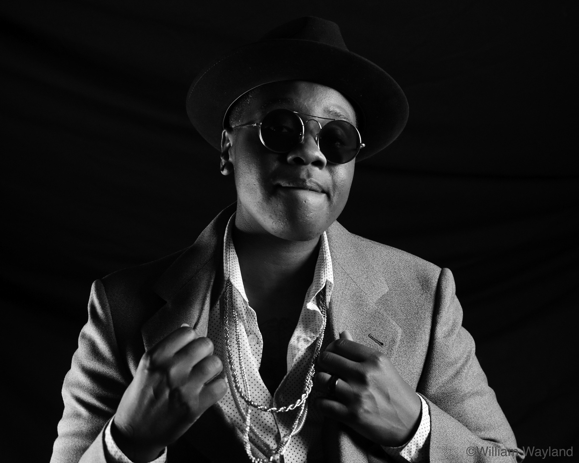 Black and white portrait of person wearing gold chains and sunglasses